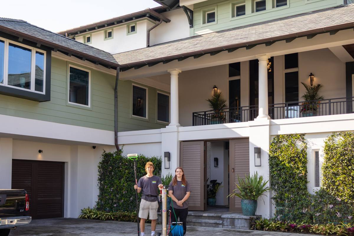 Two Swamp Wash window cleaners outside a two-story home