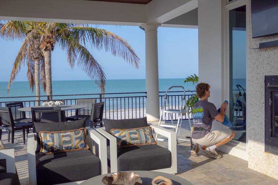 Technician cleaning glass on a beachfront lanai